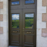 La porte d'entrée en aluminium Spencer à double vantaux avec tierce, imposte et grille alva sur une façade de maison traditionnelle