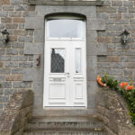La porte d'entrée en aluminium Spencer et sa grille Rustica avec tierce et imposte sur une façade de maison traditionnelle.